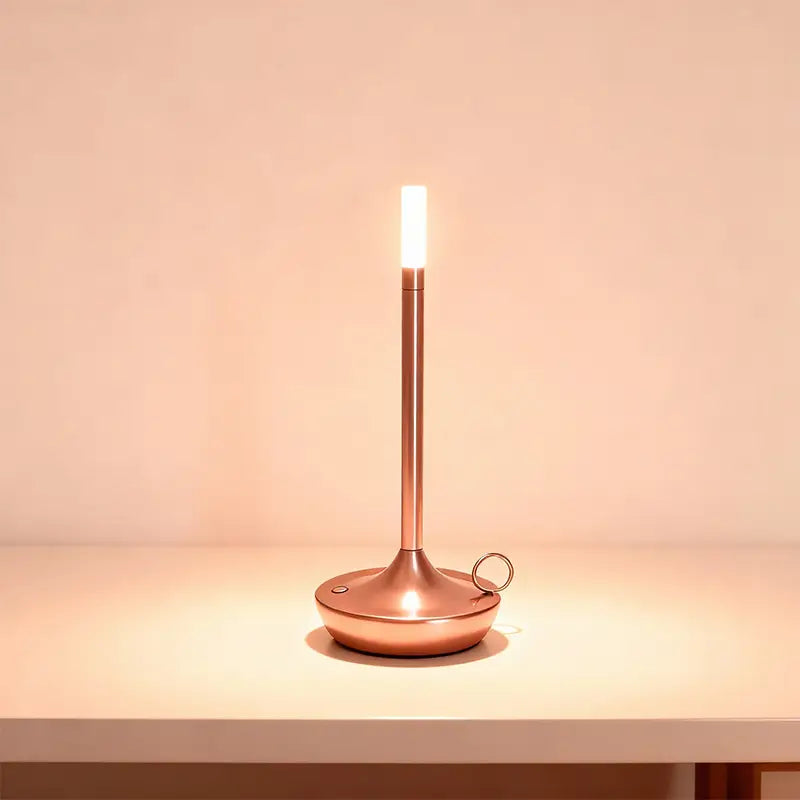 A slender rose gold LED desk lamp is on, casting a warm light.
