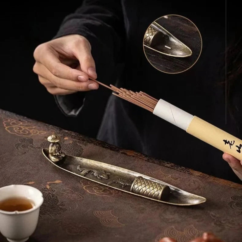Person using a tea whisk on a tea tray with a cup and teapot.
