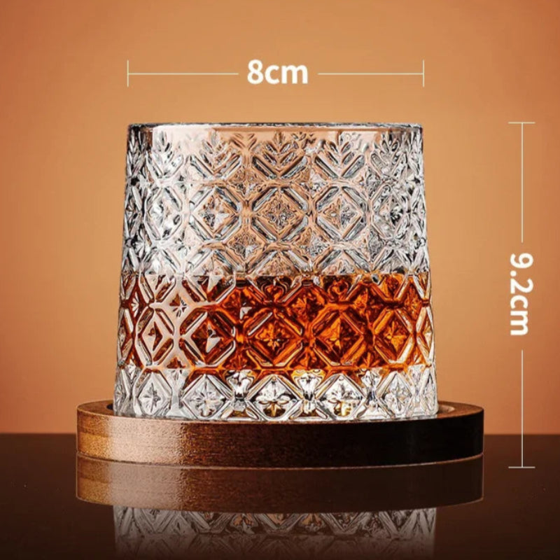 A diamond-patterned whiskey glass with amber liquid rests on a wooden coaster, with its dimensions noted.