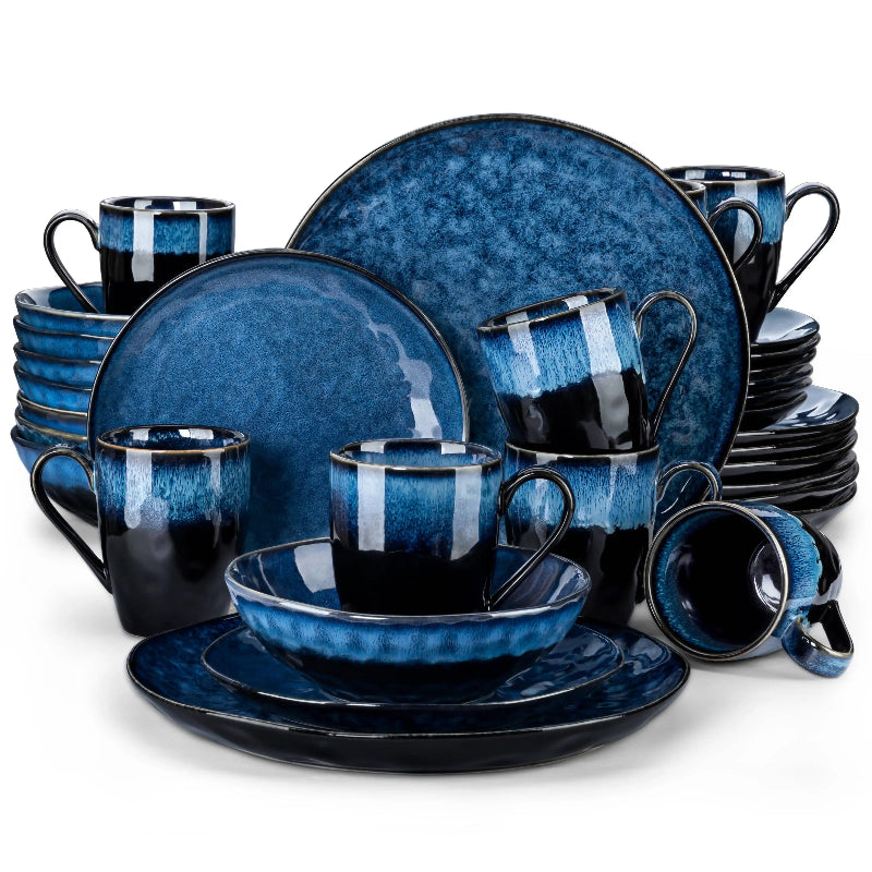 A large set of black and blue ceramic dinnerware, including plates, bowls, and mugs, is arranged in a stack against a white background.