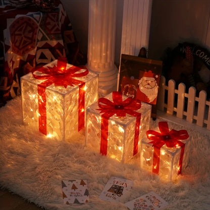 Three illuminated gift boxes with red bows on a white fluffy rug, with Christmas cards nearby.