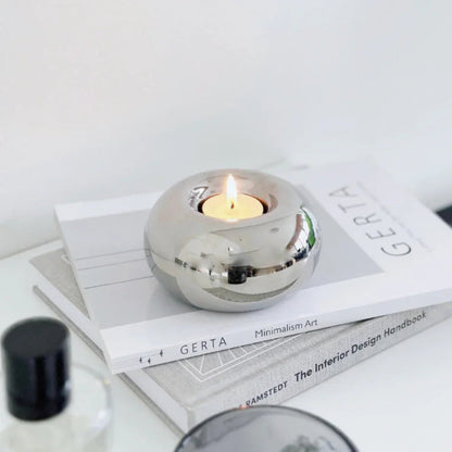 Silver spherical candle holder with a lit candle on top of books