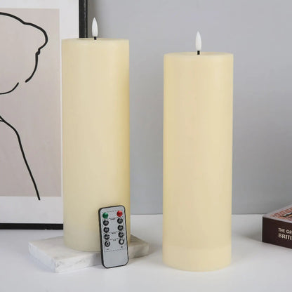 Two cream-colored flameless pillar candles, one with a remote, sit on a surface with minimalist decor.
