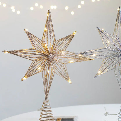 Close-up of a gold illuminated glitter wire star tree topper, with a silver one partially visible.