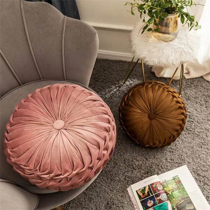 Round pink and brown cushions on a chair with a plant and magazine in the background.