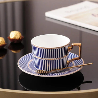 Blue and white striped tea cup and saucer with gold leaf trim and a gold spoon.