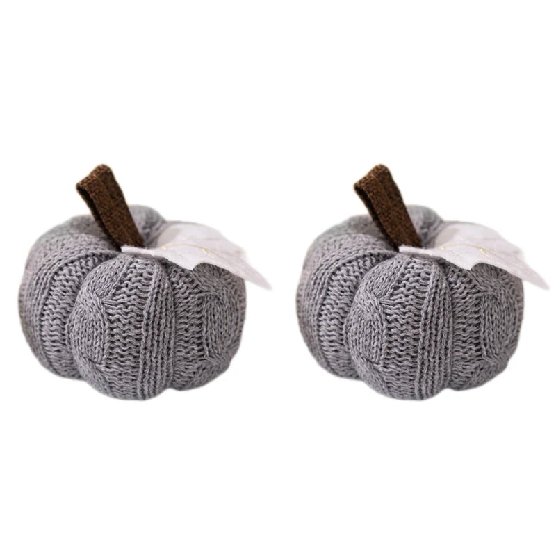 Two identical gray knitted pumpkins, each with a brown stem and a white leaf, isolated on a white background.