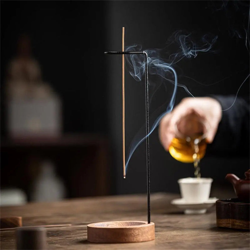 Incense burning with tea being poured in the background.