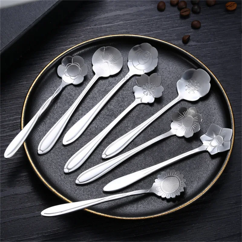 Silver flower spoons on a black tray.