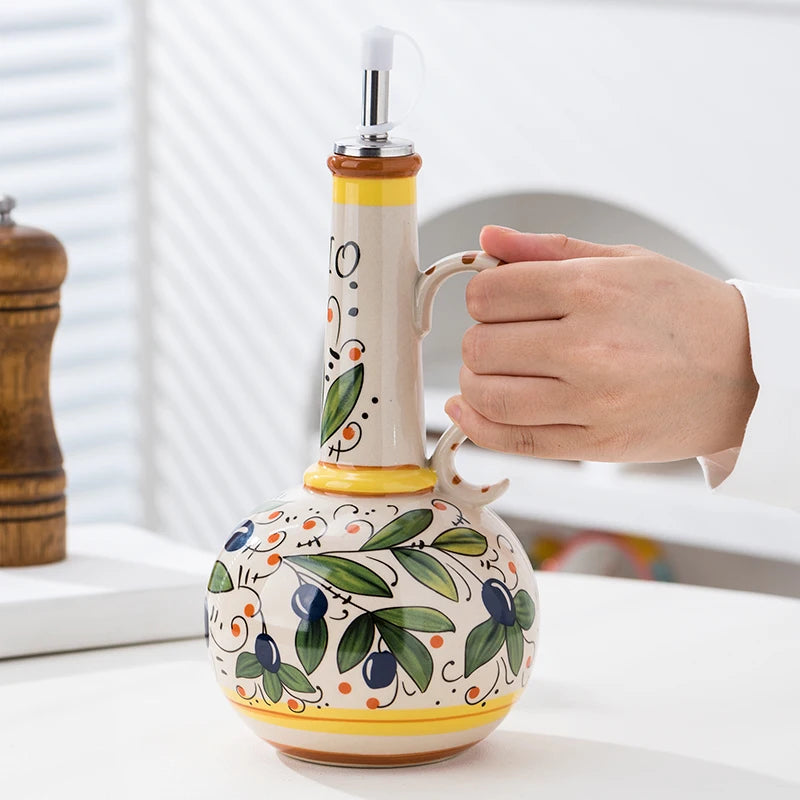 Decorative ceramic oil bottle with a hand holding it, set against a neutral background.