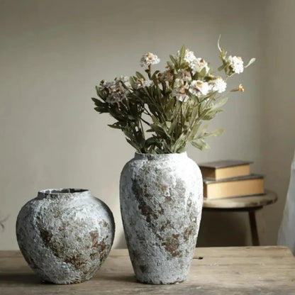 Two textured vases on a wooden surface with a neutral background