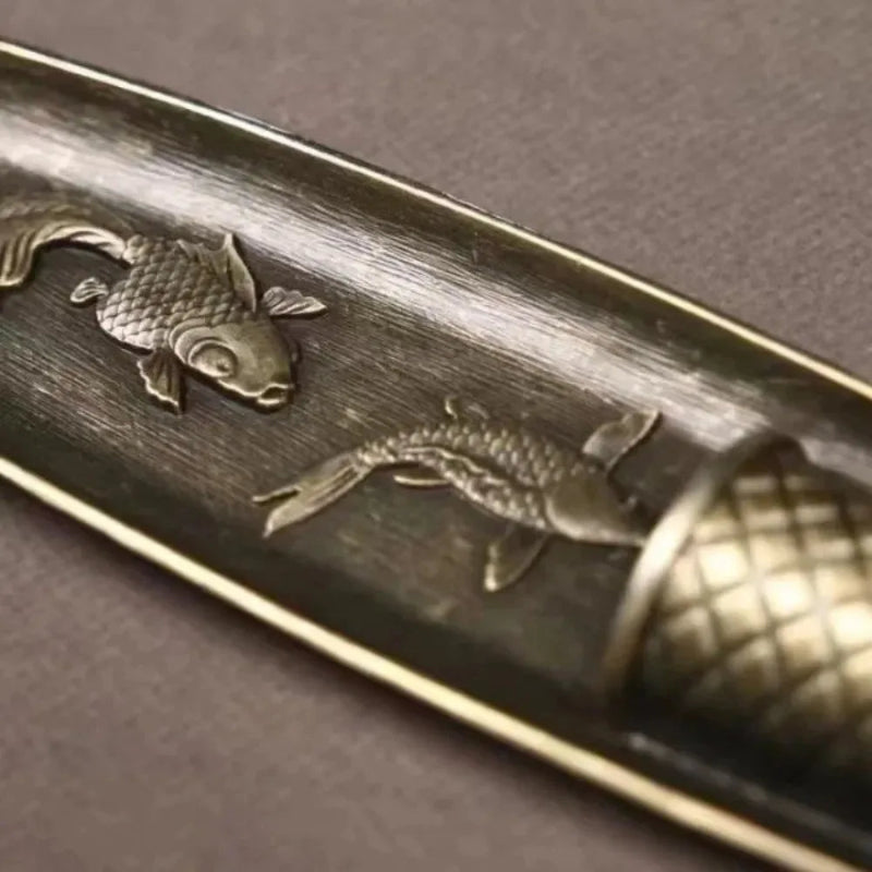 Close-up of a metallic object with fish embossing on a dark background