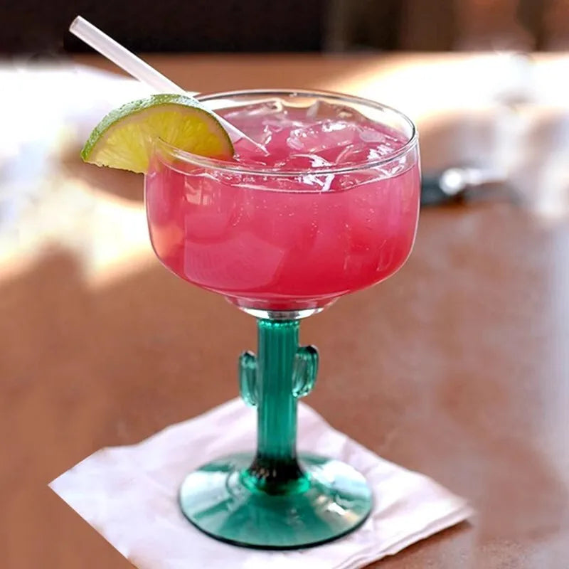 Pink cocktail in a cactus-shaped glass with a lime wedge on a blurred background