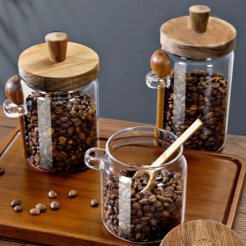 Glass jars with wooden lids filled with coffee beans on a wooden surface.