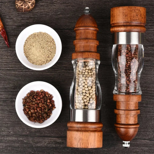 Wooden pepper grinders with spices on a wooden surface