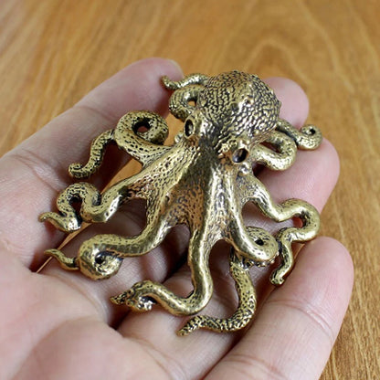 Gold octopus figurine held in a hand on a wooden surface