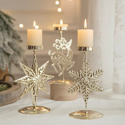 Three lit candles in gold star, reindeer, and snowflake Christmas candle holders.