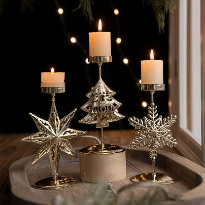 Three lighted candles in festive gold Christmas candle holders.