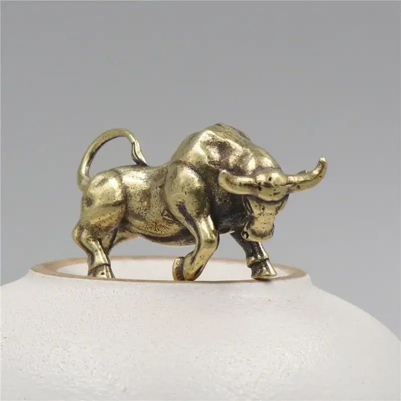 Bronze bull figurine on a white base with a gray background