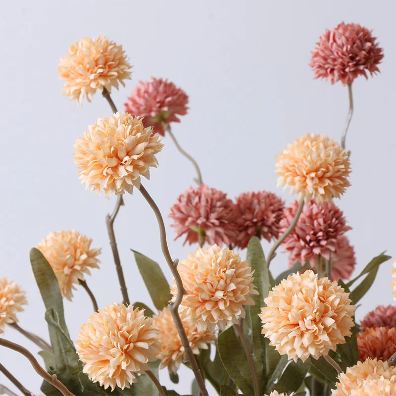 Close-up of artificial peach and pink dahlia flowers with green leaves.