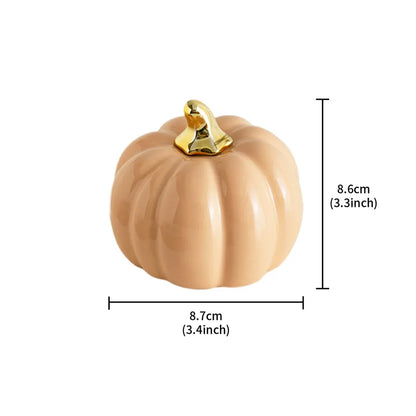 A light brown ceramic pumpkin with a gold stem is shown with its dimensions: 8.7cm (3.4 inches) wide and 8.6cm (3.3 inches) tall.