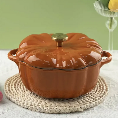 An orange, pumpkin-shaped cast iron pot with a gold knob sits on a woven placemat.