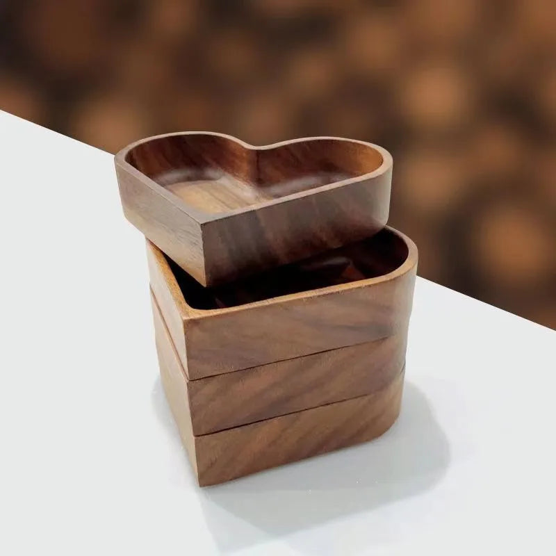 A stack of three heart-shaped wooden bowls with an additional one on top, slightly askew.