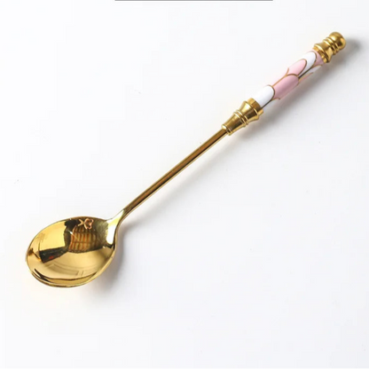Gold spoon with pink handle on a white background