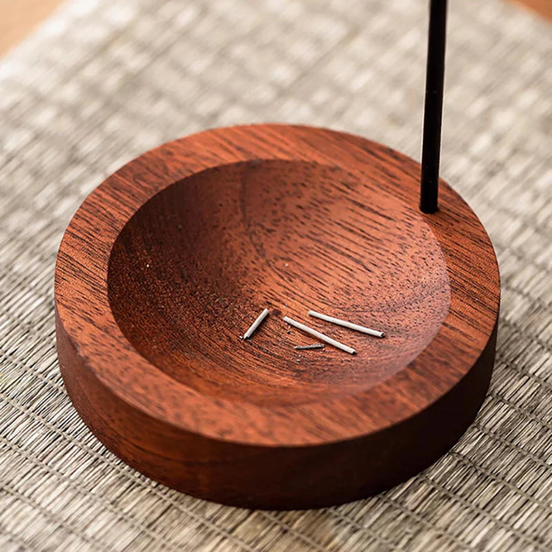 Close-up of a wooden incense holder with small remnants of incense sticks.