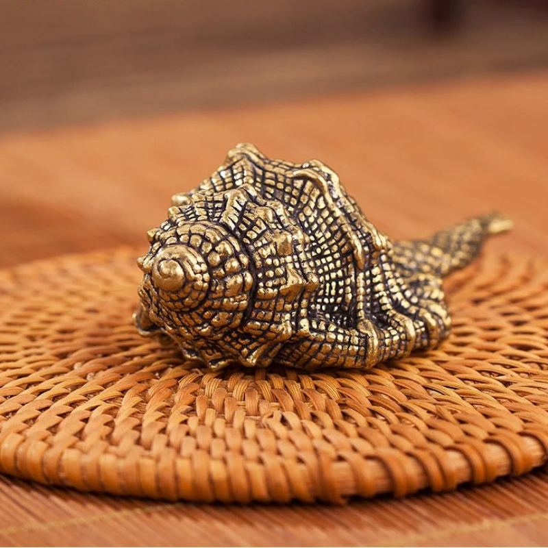 Bronze shell-shaped object on a woven surface with 'bobonuonuo' branding.
