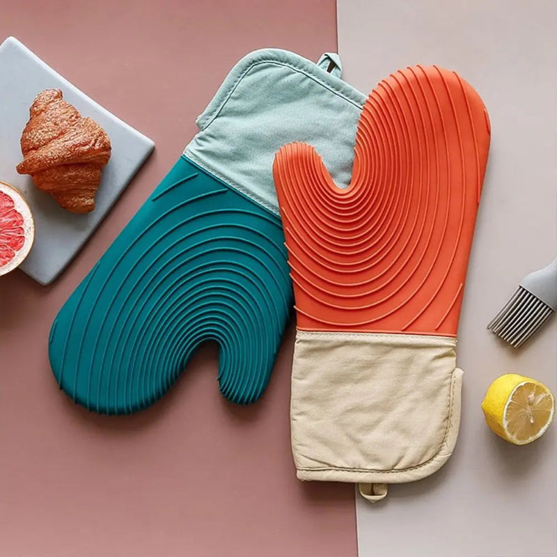 Colorful oven mitts on a kitchen counter with a croissant and lemon.