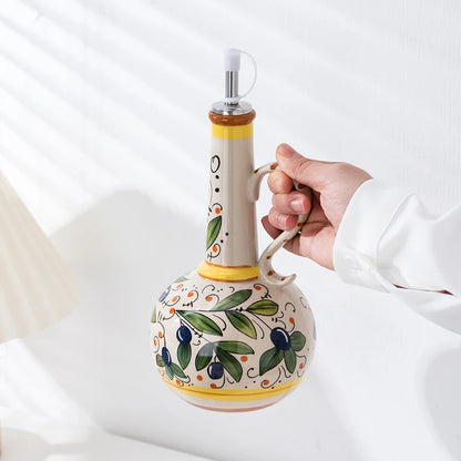 Decorative ceramic olive oil bottle with a hand holding it against a white background
