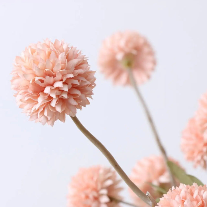 Close-up of artificial peach-colored dahlia flowers on thin stems.