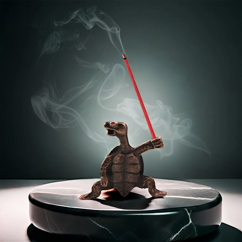 A bronze turtle incense holder on a marble base, holding a red incense stick with smoke swirling around it.
