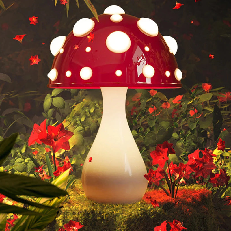 A mushroom-shaped lamp with a red cap and white spots, in a vibrant garden setting with red flowers.