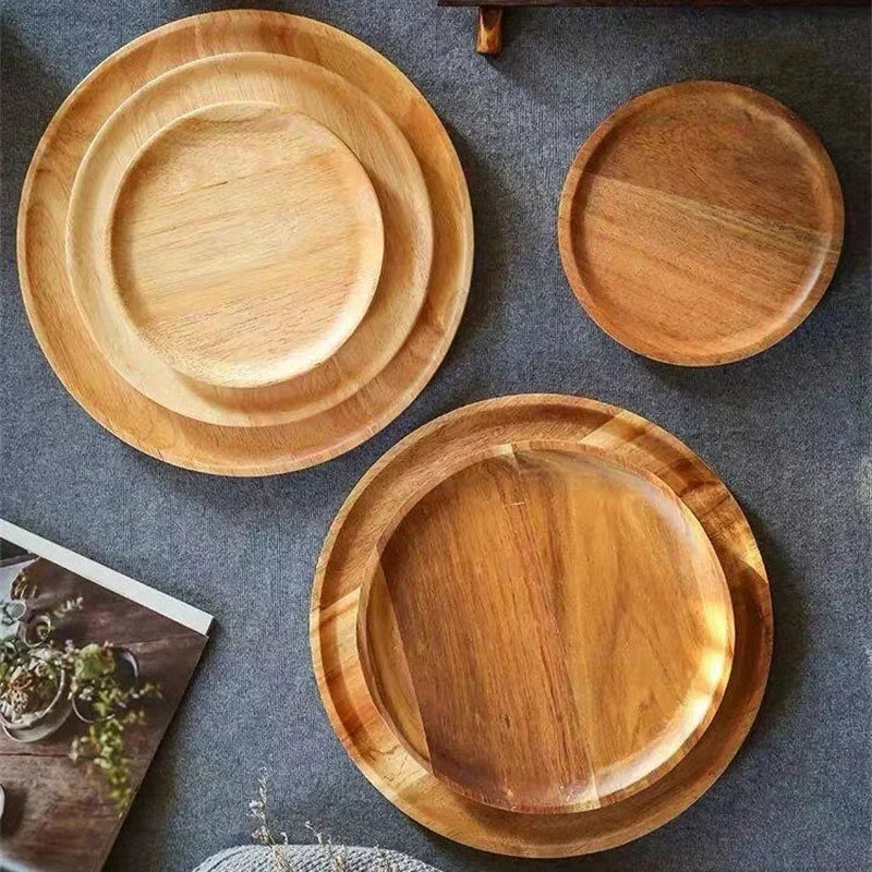 Three wooden plates of varying sizes, with two of them nested together, on a dark gray surface.
