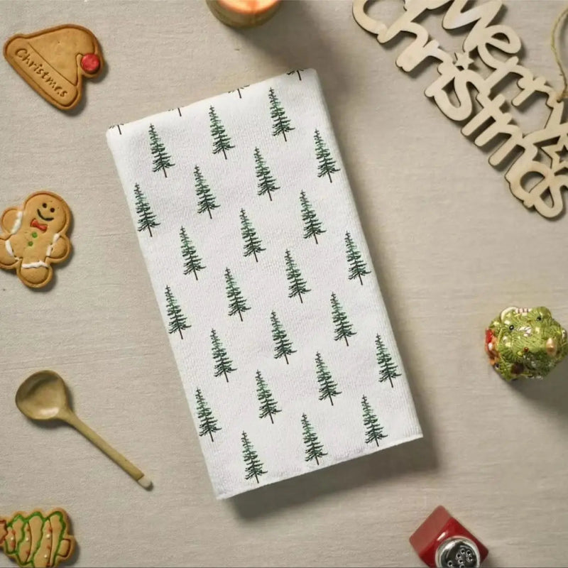 White towel with green tree pattern on a festive table with cookies and decorations