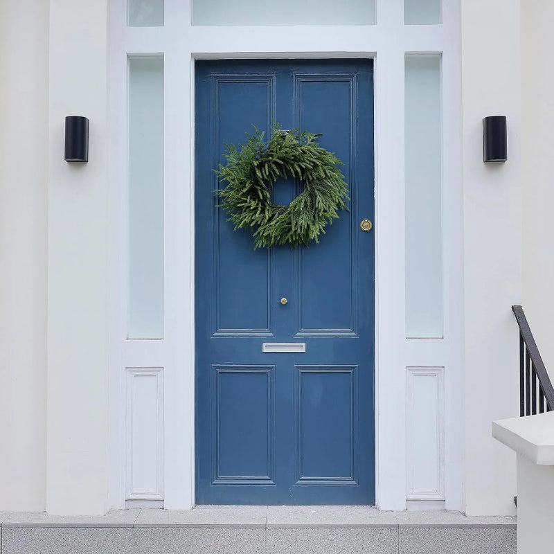 A green wreath on a blue door with white trim.