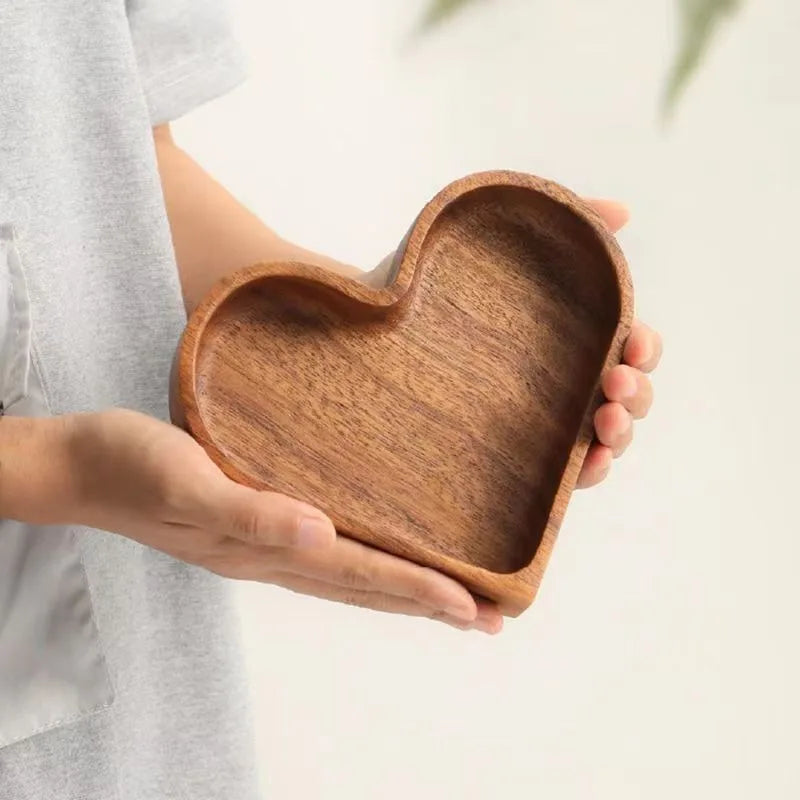 A person holds a heart-shaped wooden bowl.