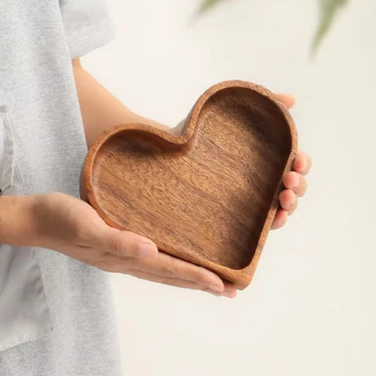 A person holds a heart-shaped wooden bowl.