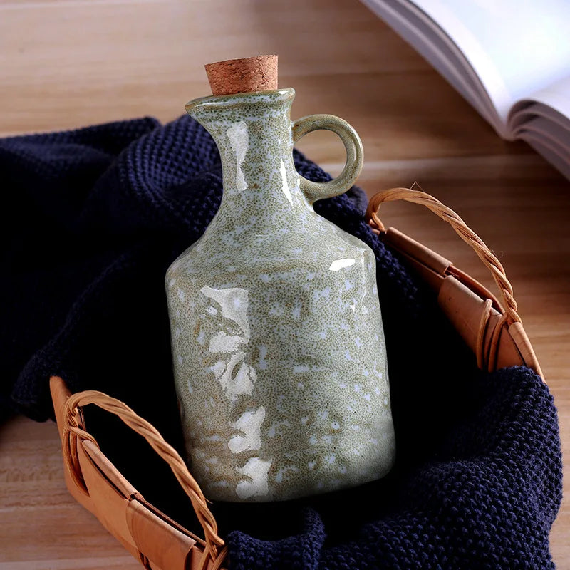 Green ceramic bottle with cork stopper on a textured surface
