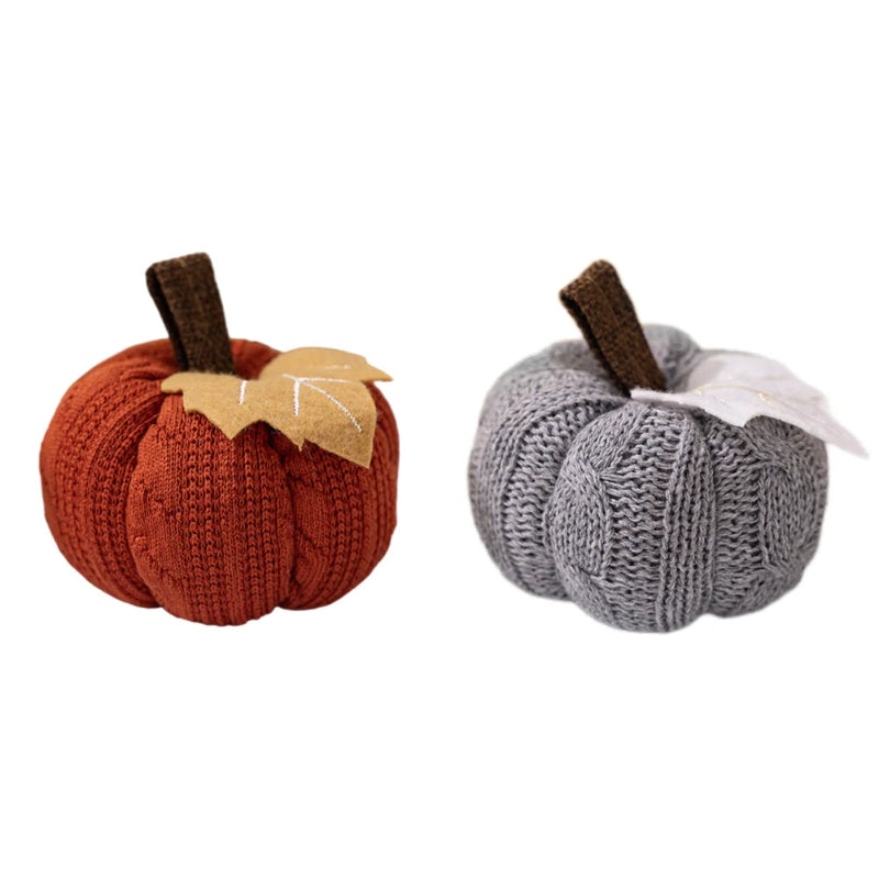 Two knitted pumpkins, one orange and one gray, each with a brown stem and a fabric leaf, isolated on a white background.