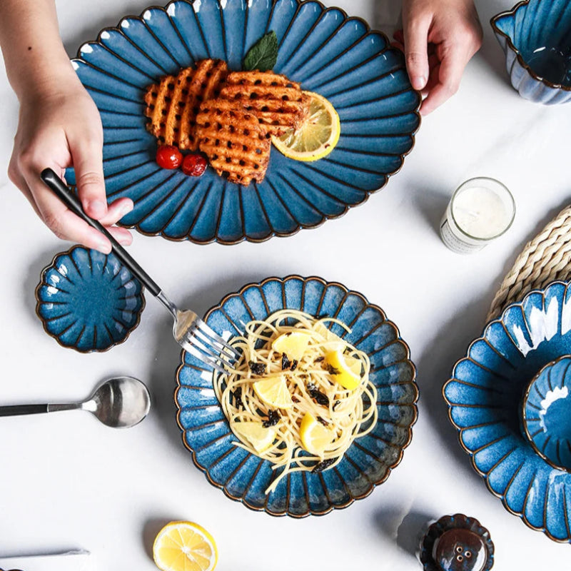 A blue ceramic dish with waffles, and another with pasta and lemon, being served.