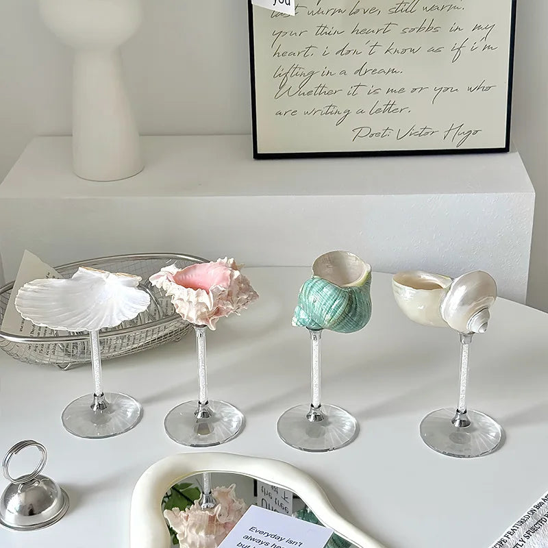 Decorative shell-shaped candle holders on a shelf with a framed quote in the background.