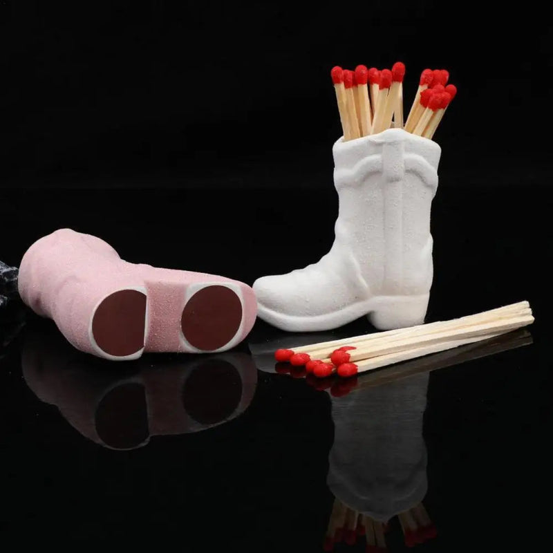 White boot-shaped matchbox with red matches on a black background