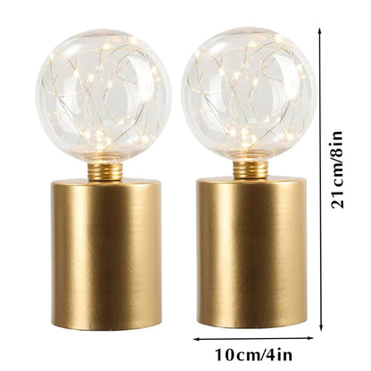 A short alt text for the user-provided image would be: A diagram of a pair of table lamps with gold cylindrical bases and clear globe shades filled with fairy lights, showing the dimensions. Each lamp is 21cm (8 inches) tall and has a 10cm (4 inches) base diameter.