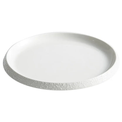 A modern white stoneware plate with a gently textured rim, featuring a minimalist design that complements both casual and elegant dining settings.