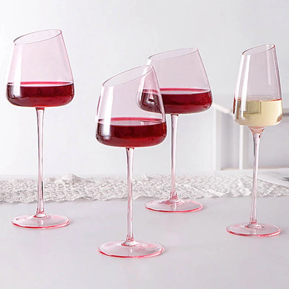 Four stemmed glasses with an angled rim, three filled with red wine and one with white wine.