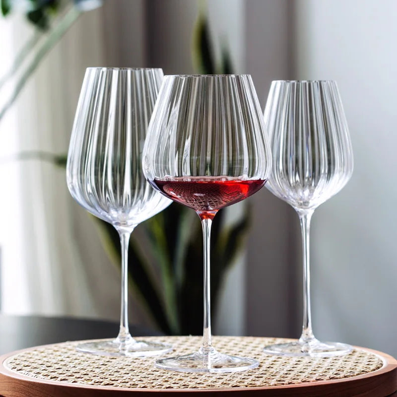 Three fluted wine glasses, one with red wine.