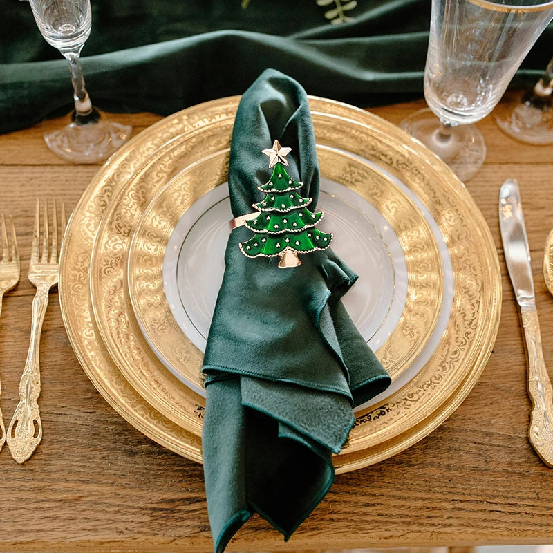 Decorative table setting with green napkin and Christmas tree napkin ring on gold charger plate.